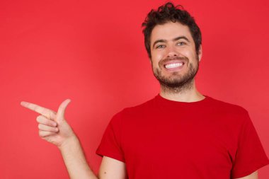 İzole edilmiş kırmızı arka plan üzerinde tişört giyen yakışıklı beyaz adam Çince işaret dili B harfini işaret ediyor..