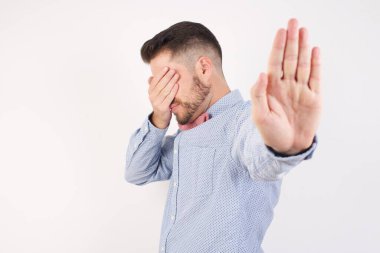 Genç adam avuçla gözlerini kapatıyor ve jest yapıyor. 