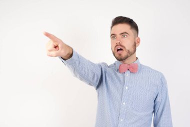 Stüdyodaki yakışıklı esmer beyaz adam, parmağını ileri uzatarak şaşırmış, ağzı açık, şaşırmış, ön tarafta bir şey var..