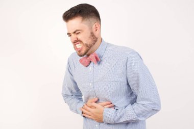 Mide bulantısı, acı verici hastalıklar yüzünden elleri karnında olan hasta genç bir adam. Ache kavramı.