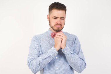 Resmi gömlek ve papyon giymiş üzgün Avrupalı bir adamın güzel yüzü beyaz stüdyo arka planına karşı çaresiz ve üzgün gözlerinden yaşlar boşalan hüzünlü bir yüz ifadesi ve duygu konsepti yüzünden depresyona girmiş bir şekilde poz veriyor.