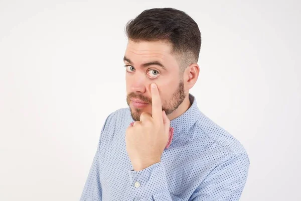 European man dressed in formal shirt and bow tie poses against white studio background Pointing to the eye watching you gesture, suspicious expression.