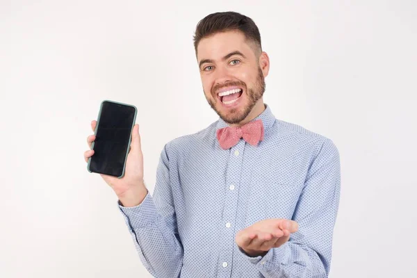 在白人工作室里快乐的白人男人 戴着领结 手持手机 带着智能手机 — 图库照片