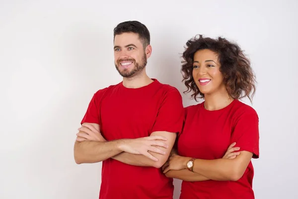 Young couple wearing red t-shirts posing over studio background