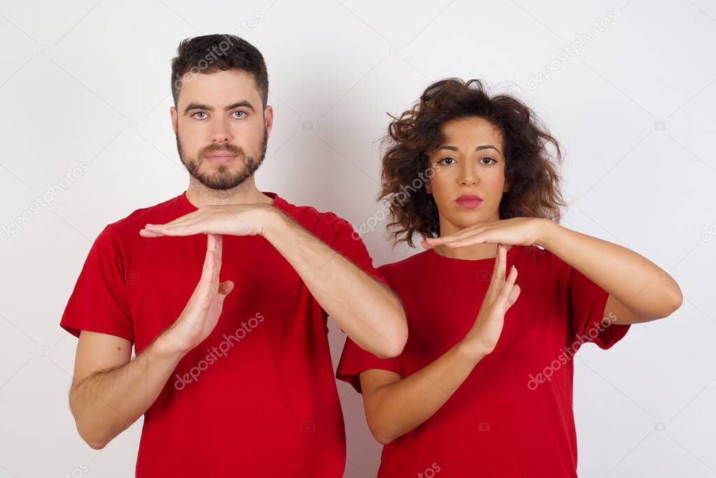 Young couple wearing red t-shirts posing over studio background