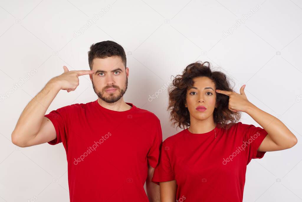 brunette hair man and woman in studio, make suicide gestures and imitates guns with hands, curves lips keeps two fingers on temple, shoots, problem 