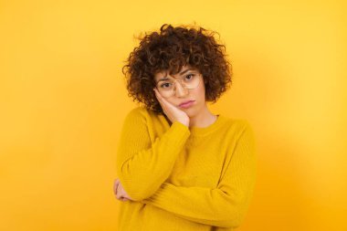 Üzgün, yorgun bir kadın, elleri yanağında hasta görünüyor. 