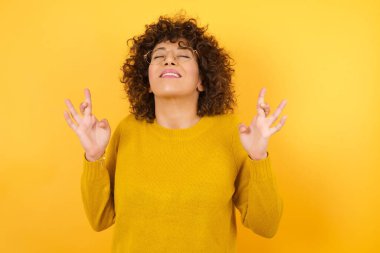 Parmaklarını çapraz yapıp umut ve gözleri kapalı gülümseyen genç bir kadın. Şans ve batıl inanç.