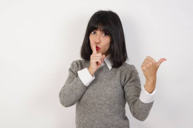 Genç bir kadın sessiz olmak istiyor. Parmakları dudaklarında, elleri yana doğru uzanıyor. Sessizlik ve gizli konsept.