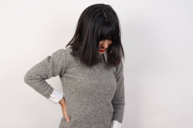 Genç bir kadın sırt ağrısı çekiyor, elleriyle dokunuyor, kas ağrısı çekiyor.