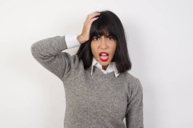 Utanmış, beyaz tenli, şok olmuş bir kadın, şaşkınlığını dile getiriyor, kafası karışmış bir adam içeride poz veriyor.