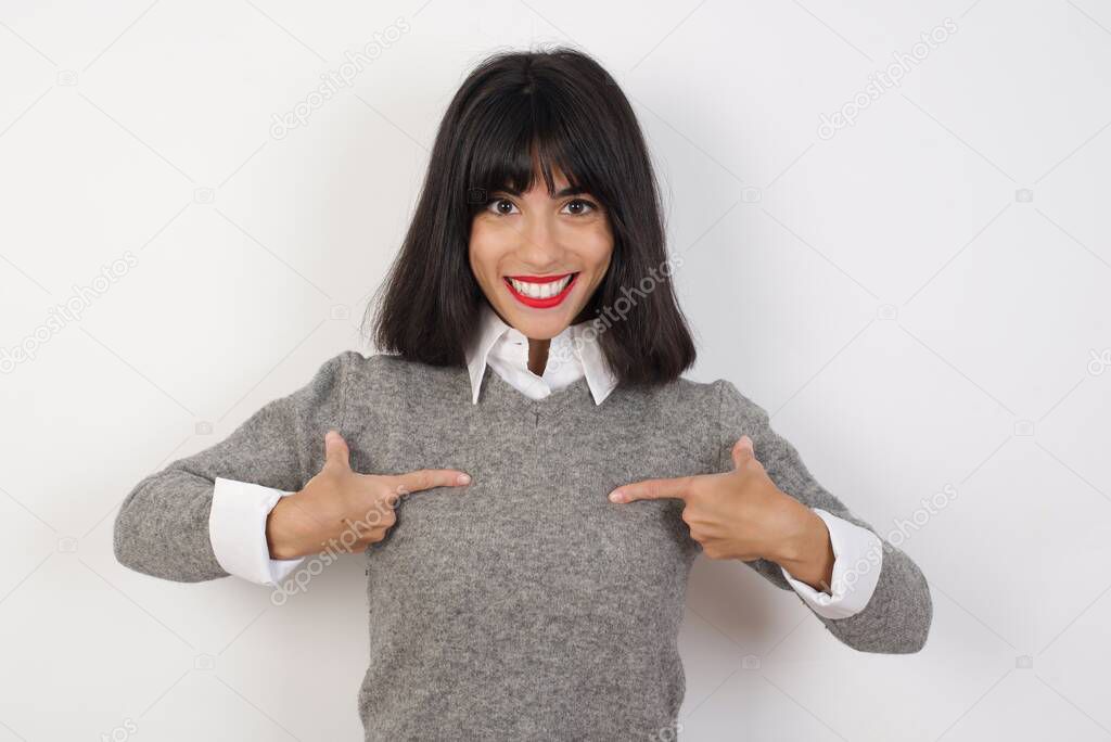 Horizontal shot of cheerful stylish woman points at body, being in good mood after going shopping and making successful purchases