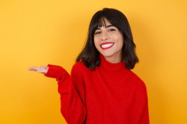 Avuç içi ile sunan ve gösteren ve kameraya bakan genç bir kadın..