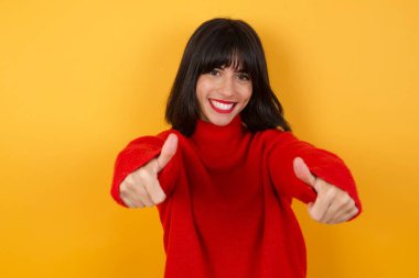 Elle olumlu jest yapmayı onaylayan genç ve güzel bir kadın. Başparmağıyla gülümsüyor ve başarı için mutlu. Kazanan jest.