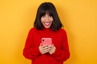 Neşeli, sevimli, çekici, beyaz bir kadın elinde telefonla. 