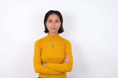 Kollarını kavuşturup kameraya bakan ciddi bir yüz modeli. Pozitif kişi.