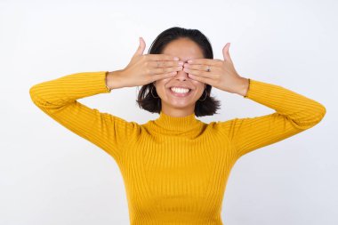 Model, neşeli ve komik gülümseyen ellerle gözlerini kapatıyor. Kör kavram.