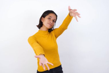 Güzel, genç bir kadın kameraya bakıyor. Sarılmak için kollarını açmış gülümsüyor. Mutluluğu kucaklayan neşeli bir ifade..