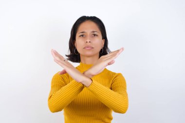 Reddedilmiş güzel genç bir kadın kollarını kavuşturup negatif işaret veriyor, kızgın bir yüz ifadesi takınıyor.