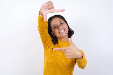 Güzel genç bir kadın elleriyle parmak çerçevesi yapıyor. Yaratıcılık ve fotoğrafçılık kavramı.