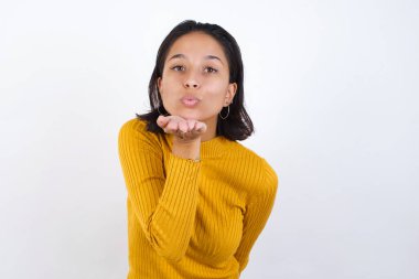 Güzel, genç bir kadın kameraya bakıyor, havada elle öpücük savuruyor güzel ve seksi. Aşk ifadesi.