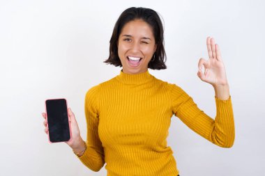 Model cep telefonunu tutuyor ve tamam işareti gösteriyor 