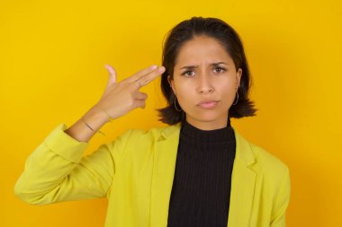 Mutsuz Model intihar jesti yapıyor ve tabancayı eliyle taklit ediyor, dudaklarını kıvırıyor, iki parmağını şakakta tutuyor.