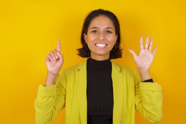 Model kendini beğenmiş ve mutlu gülümserken altı numarayı gösteriyor ve işaret ediyor..