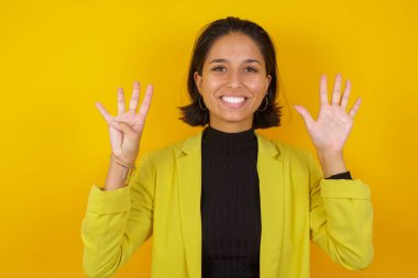 Model dokuz numaralı parmaklarıyla gösterip işaret ederken kendinden emin ve mutlu gülümsüyor.