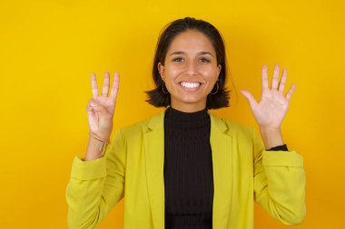 Model kendini beğenmiş ve mutlu gülümserken sekiz numarayı gösteriyor ve işaret ediyor..