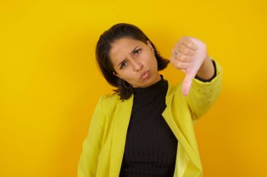  Güzel genç bir kadın sinirli, sinirli, hayal kırıklığına uğramış ya da hoşnutsuz, ciddi bir bakışla baş parmağını aşağı gösteren. 