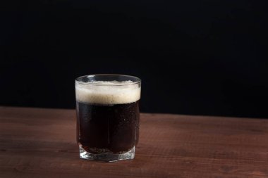 bir cam ahşap bir masa üzerinde köpük koyu bira