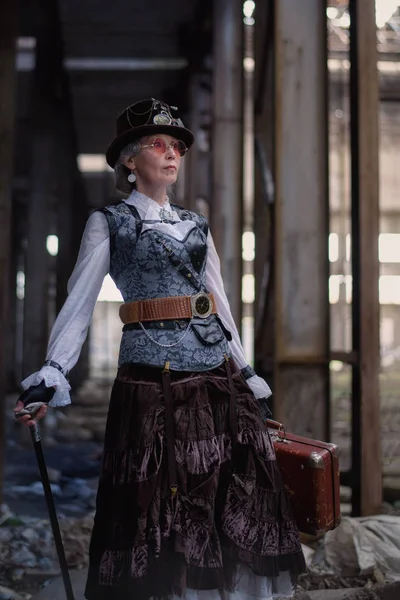 Dame âgée en costume steampunk dans une usine abandonnée avec — Photo