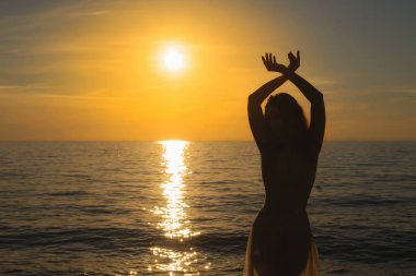 Sadık kadın silueti gündoğumu sıcak bir arka plan ile kumsalda güneş tutan bir arka ışık açık görünüm