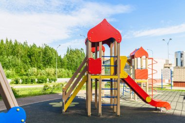Güneş ışığında sabah yeşil ağaçlarla çevrili halka açık parkta bahçe etkinlikleri çocuk oyun alanı. Çocuklar koşu, kaydırma, salıncak, modern oyun alanında tahterevalli. Kentsel mahalle çocukluk kavramı.