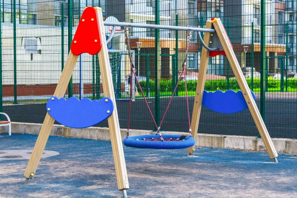 Barnlekplats på gården aktiviteter i offentlig Park omgiven av gröna träd på Sunlight morgon. Barn springa, glida, Swing, gungbräda på modern lekplats. Urban Neighborhood barndoms koncept. — Stockfoto