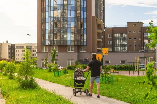 Vater Vater mit neugeborenem Kinderwagen vor dem Sommerabend-Sonnenuntergang in den Straßen der Stadt; Familienfreizeitkonzept — Stockfoto