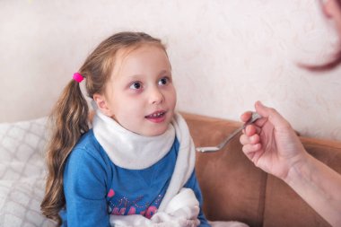 Çocuk ilaç alıyor. Yatakta eşarp yatan hasta kız