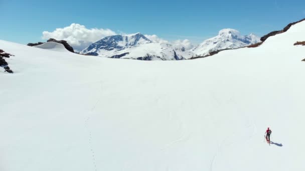 航空写真 飛んでハイカー アルプスのパノラマの景色 スキー旅行登山雪山雪に覆われた山の頂上に向かって歩いて逆境を征服 成功を達成します — ストック動画