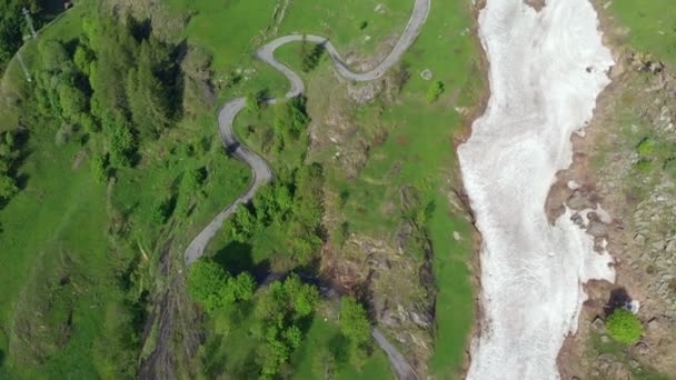 飞越蜿蜒的山路上的意大利阿尔卑斯山 越过绿色的草地和牧场 废弃的山村和雪崩在高空 冒险的道路旅行在夏季 — 图库视频影像