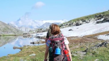 Backpacker patika pastoral dağ manzara mavi göl, yüksek dağ tepe ve buzul üzerinde hiking. Alpler yaz maceralara. Ağır çekim.