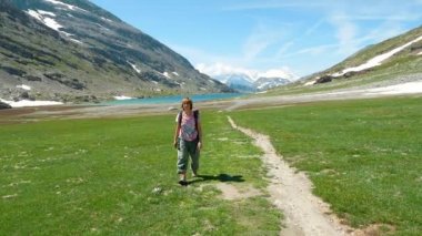 Backpacker patika pastoral dağ manzara mavi göl, yüksek dağ tepe ve buzul üzerinde hiking. Alpler yaz maceralara. Ağır çekim.