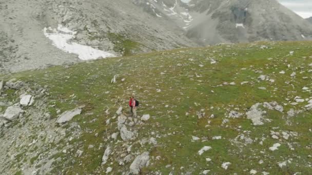 空中飞行 在高山峡谷上的两个徒步旅行者周围飞来飞去看全景 阿尔卑斯山上的夏日探险 颜色分级 — 图库视频影像