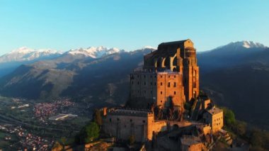 Hava: eski ortaçağ abbey adlı uçan uçak dağın tepesinde, gündoğumu, karlı Alpler'in çarpıcı arka plan üzerinde tünemiş. Sacra di San Michele (İtalyan) - Saint Michel Abbey (İngilizce traslation) - Torino, İtalya