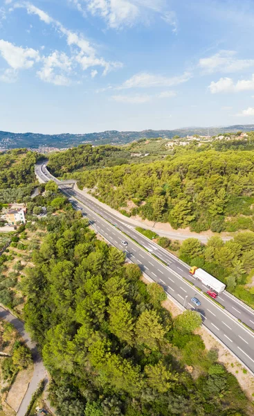 Aerial view of multiple lane highway crossing villages and forest hills (Autostrada dei Fiori - A10) Liguria Italy