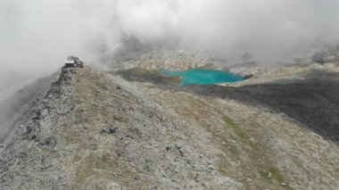 Hava: yüksek irtifa manzara, kayalık dağ zirveleri ve eski askeri tahkimat üstte mavi dağ Gölü üzerinde uçan. Alpler, Andes, Himalaya kavramı. Yerli Cinelike D-yetersiz günlük düz renk profili.