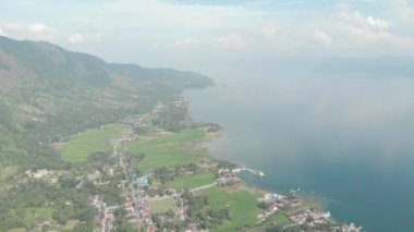 Havadan: Sumatra Endonezya yukarısında Toba ve Samosir Adası Gölü. Su, batak köyleri, yeşil pirinç tarlaları, Ekvator ormanı ile kaplı büyük volkanik Kaldera. Yerel cinelike D-log renk profili.