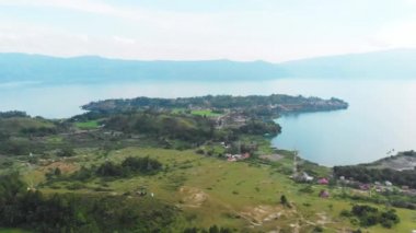Hava: Toba Gölü ve Sumatra Endonezya 'dan Samosir Adası manzarası. Büyük volkanik kaldera suyla kaplı, geleneksel Batak köyleri, yeşil pirinç tarlaları, ekvatoral orman.