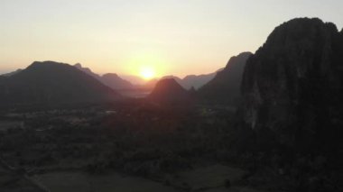 Hava: Laos, Asya 'da Vang Vieng Backpacker seyahat noktası. Manzara kayalıkları ve kaya Pinnacles üzerinde günbatımı, pirinç tarlaları Vadisi, çarpıcı manzara. Yerel cinelike D-log renk profili.