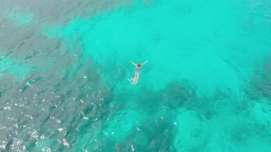 Havadan: kadın turkuaz su mercan resifi tropikal Karayip Deniz Endonezya Sulawesi Wakatobi Marine National Park, turist dalış seyahat hedef üzerinde yüzme. Yerel cinelike D-log renk profili.